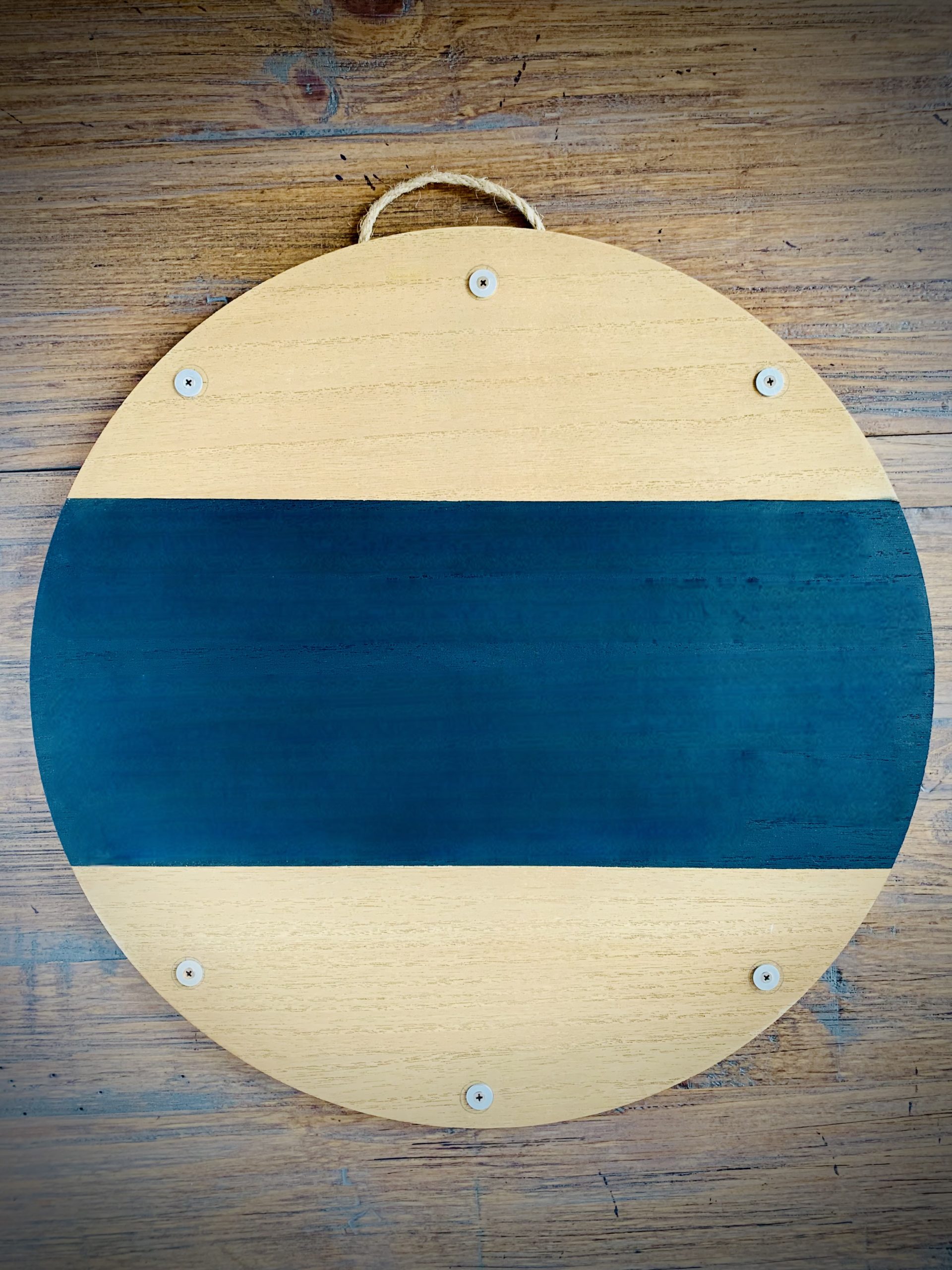Round blank EverWreath wooden base with natural wood finish, black center band, hanging rope, and attachment points on a wood background