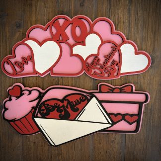Interchangeable EverWreath Valentine’s Day plate set with pink and red hearts, XOXO lettering, a cupcake, gift box, and love letter on a wood background