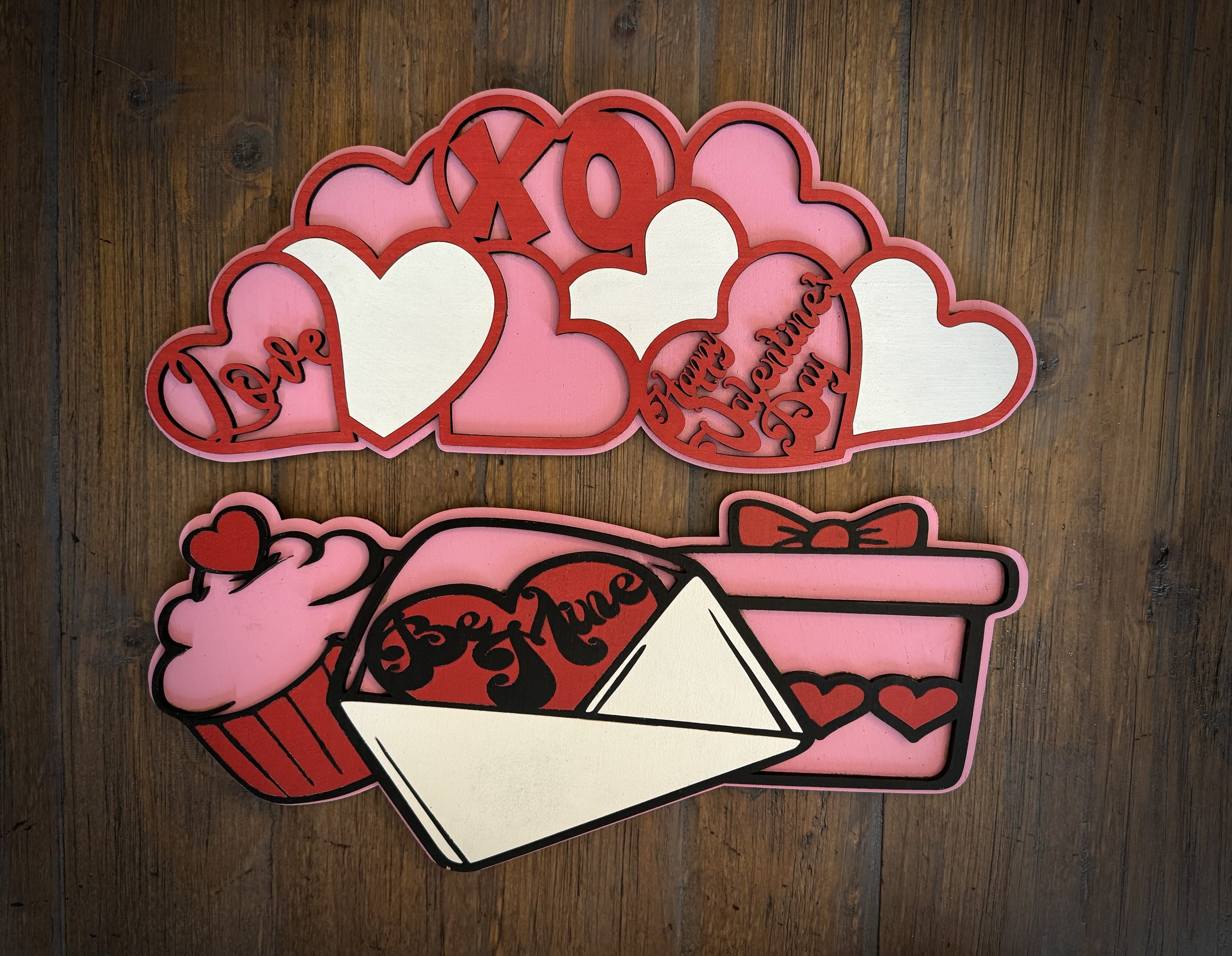 Interchangeable EverWreath Valentine’s Day plate set with pink and red hearts, XOXO lettering, a cupcake, gift box, and love letter on a wood background