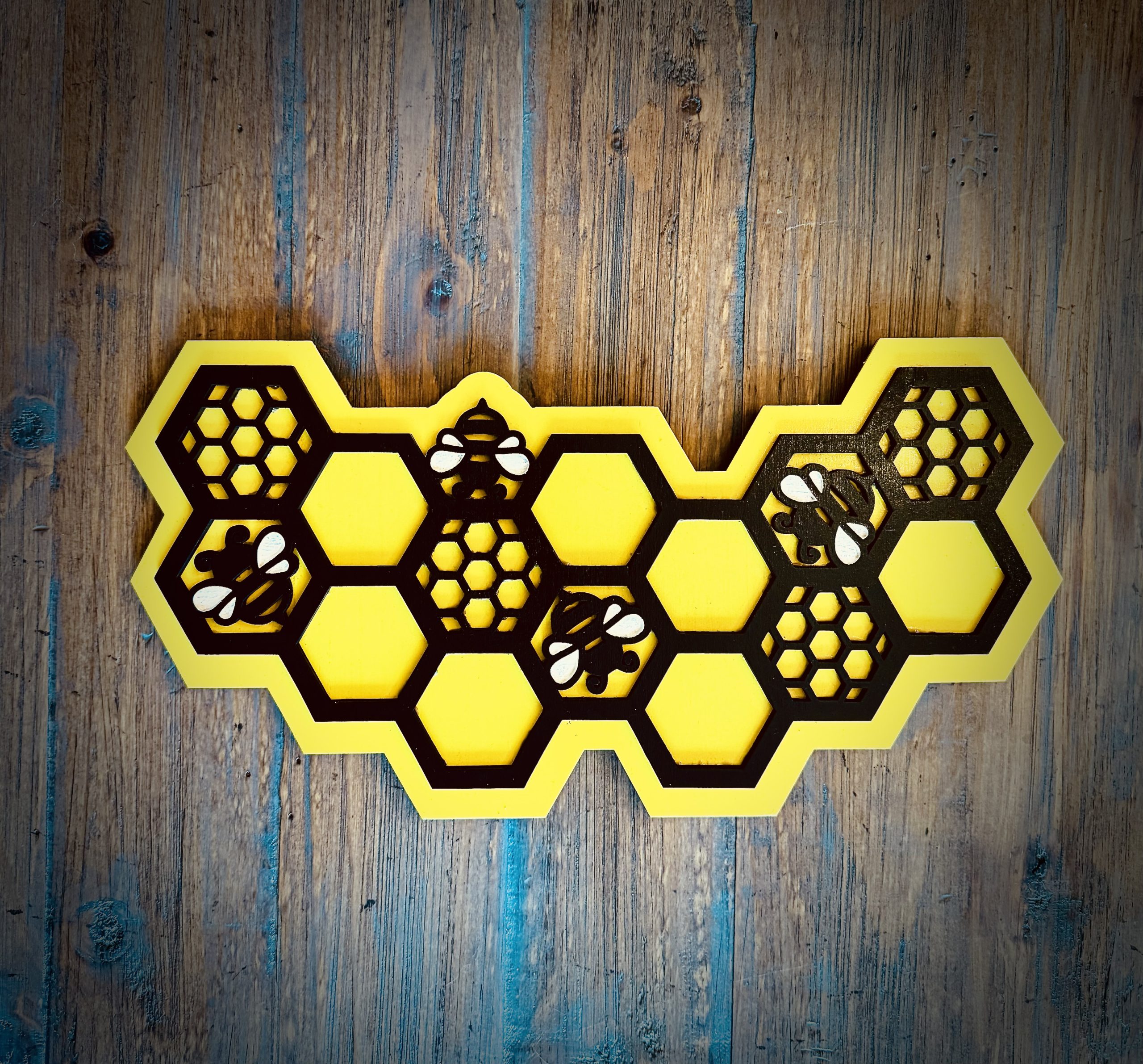 Interchangeable EverWreath honey bee plate with yellow honeycomb design and bee details on a wood background