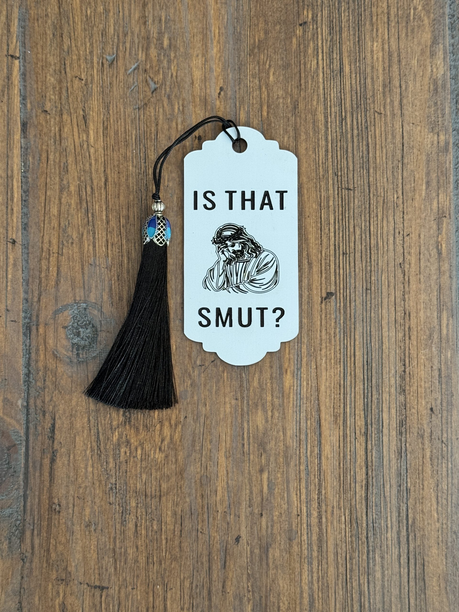 White acrylic bookmark with disappointed Jesus illustration, “Is That Smut?” text, and black tassel