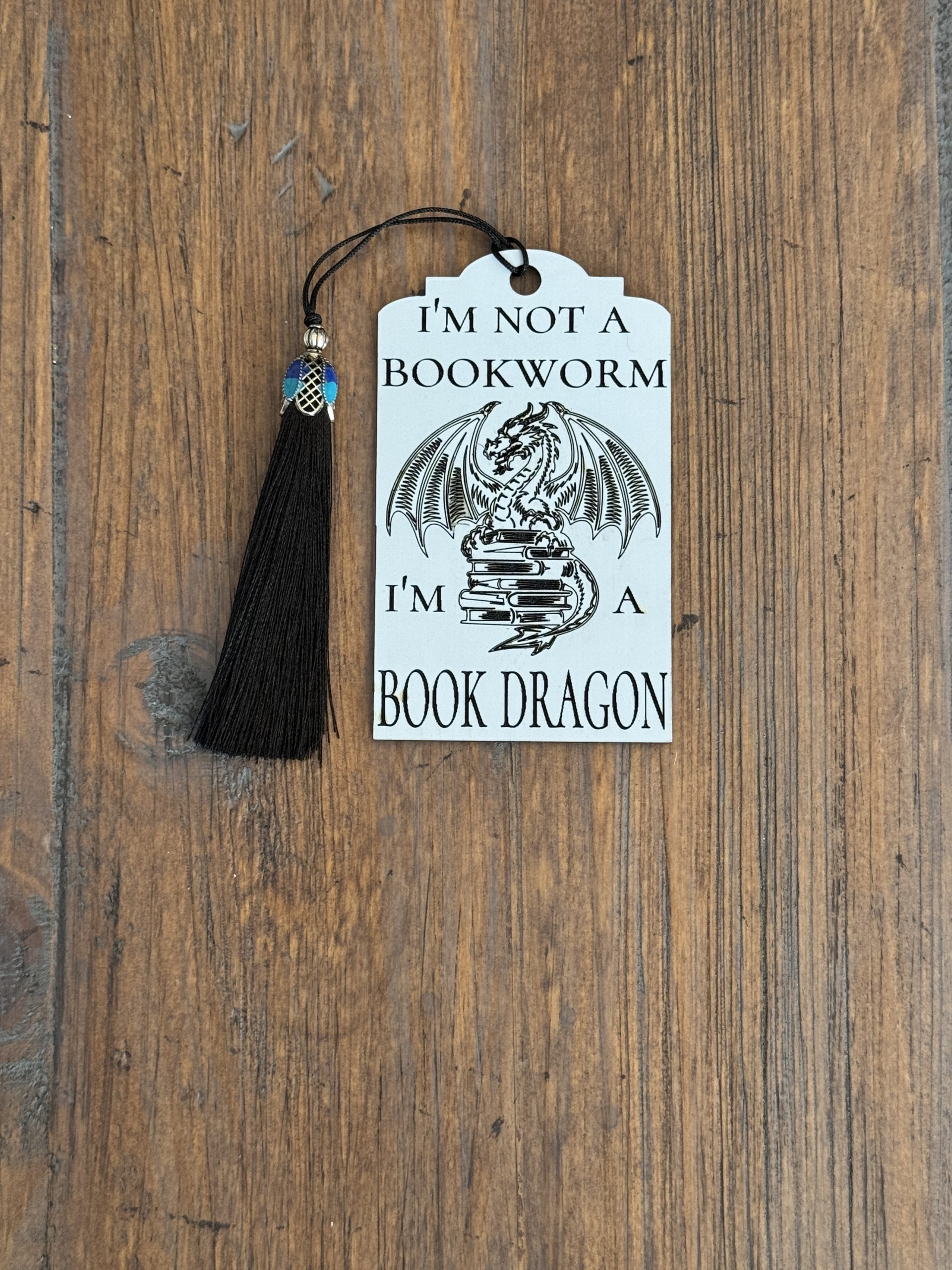 White acrylic bookmark with “I’m Not a Bookworm, I'm a Book Dragon” text and black tassel