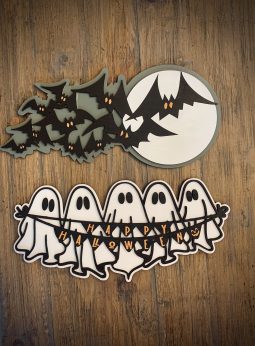 Interchangeable EverWreath Halloween plate set with flying bats, a full moon, and five ghosts holding a “Happy Halloween” banner on a wood background