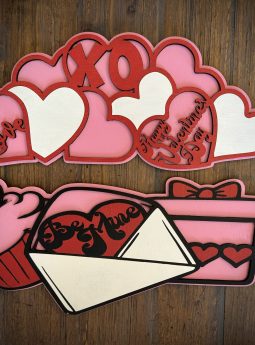 Interchangeable EverWreath Valentine’s Day plate set with pink and red hearts, XOXO lettering, a cupcake, gift box, and love letter on a wood background